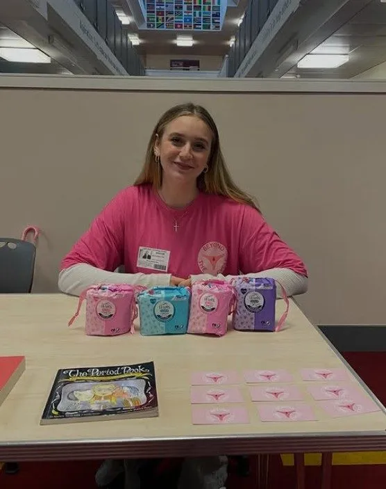 Beyond the Cycle volunteer with period care kits at a school event