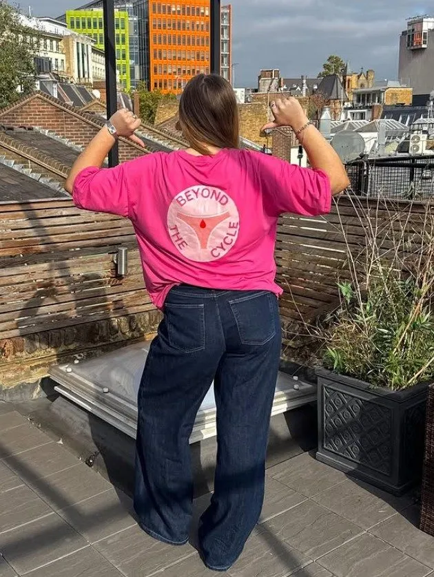 Back of a pink Beyond the Cycle t-shirt on a London rooftop